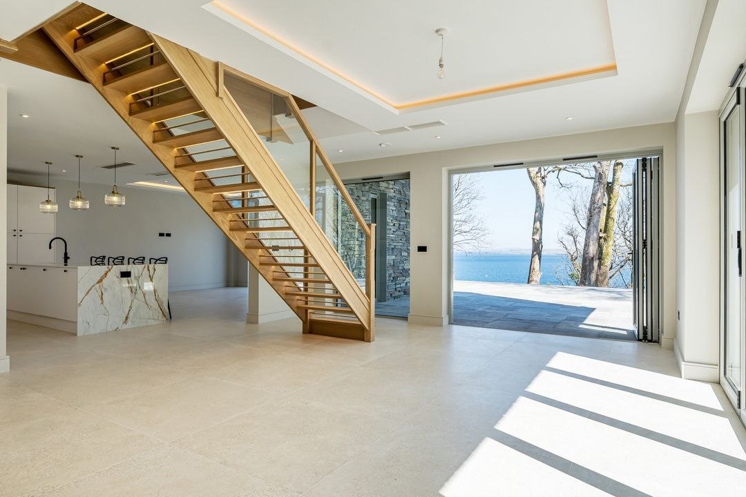 Oak staircase and open-plan coastal interior with sea view